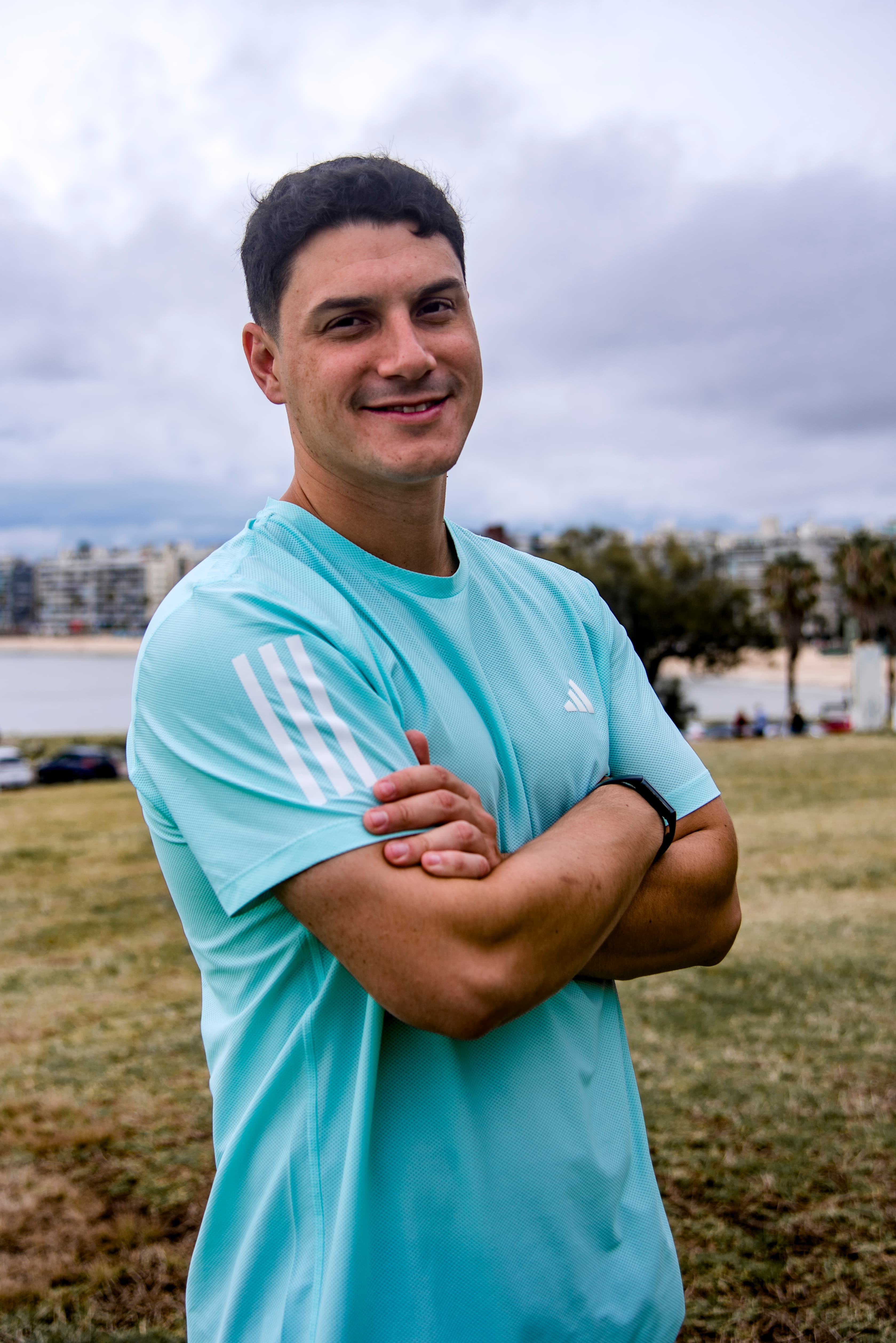 Nico Cardozo mirando a la cámara, vistiendo ropa deportiva y sonriendo mientras cruza los brazos